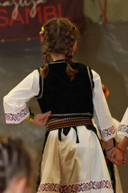 Mädchen mit Zöpfen und besticktem Trachtenhemd tanzt auf der Bühne